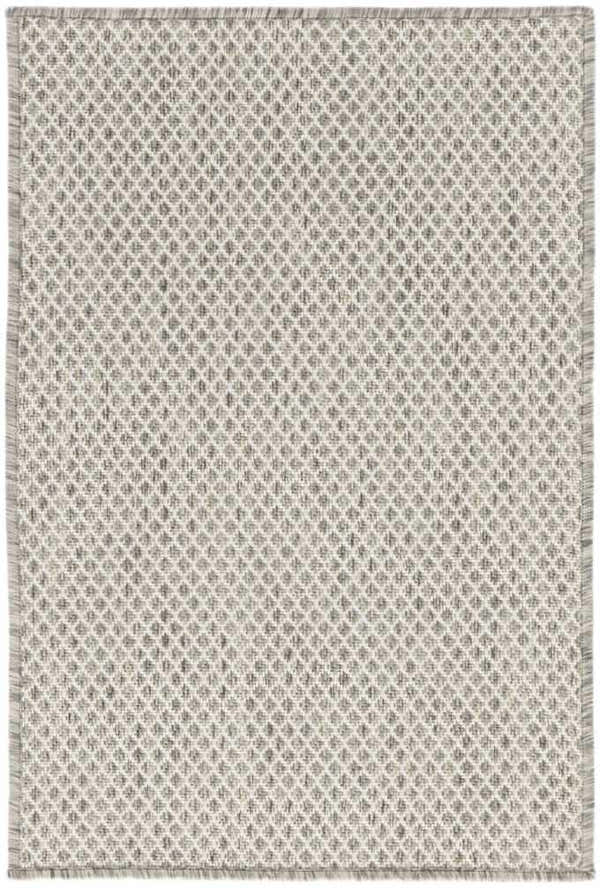 Close-up of the Nourison Courtyard Ivory Silver rug. Features a diamond pattern and fringed edges.
