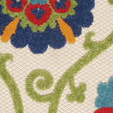 Close up of Nourison Aloha Blue Multicolor rug showing floral design in blue, green, red, and orange on a textured cream background.