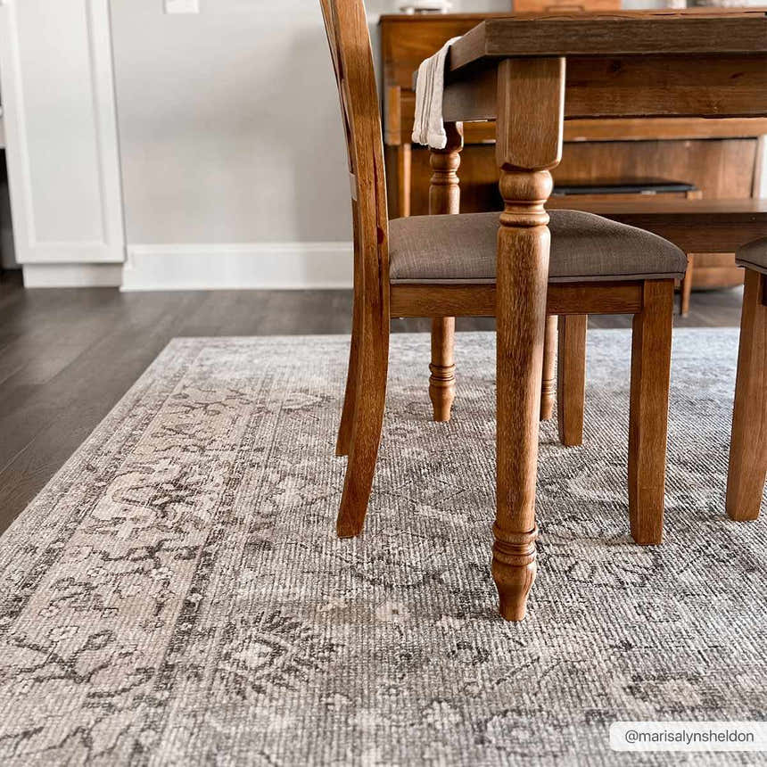Dining room scene with a Becki Owens x LIVABLISS Davina rug in charcoal, light gray, and taupe under a wooden table. Roomscene-Rectangle