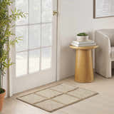 Entryway with a DKNY Pure Framework Camel rug, wood floors, white door, side table, and neutral chair.