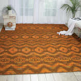 Living room scene with Nourison Spectrum Flame Chocolate rug, tribal pattern, white bench, and bright natural light.