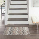 Entryway with stairs and a Nourison Elation Grey Ivory rug on dark wood floors. Modern bench and table.