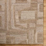Close-up of the Brasen Tan Area Rug showing its beige, tan, and taupe geometric pattern and hand-tufted wool texture. Corner