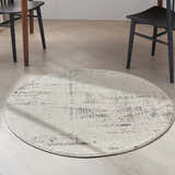 Dining room with a round Calvin Klein CK950 Rush Ivory Beige rug under chairs.