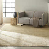 Living room scene with a Calvin Klein Mesa Gypsum rug, gray sofa, wood side table, and natural light.