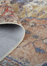 Close-up of the Feizy Percy rug showing the red, tan, and blue medallion pattern and the rug's backing. Fold
