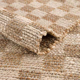 Close-up of the beige and tan checkered pattern and jute texture of the Ionut Checkered Jute Area Rug. Fold