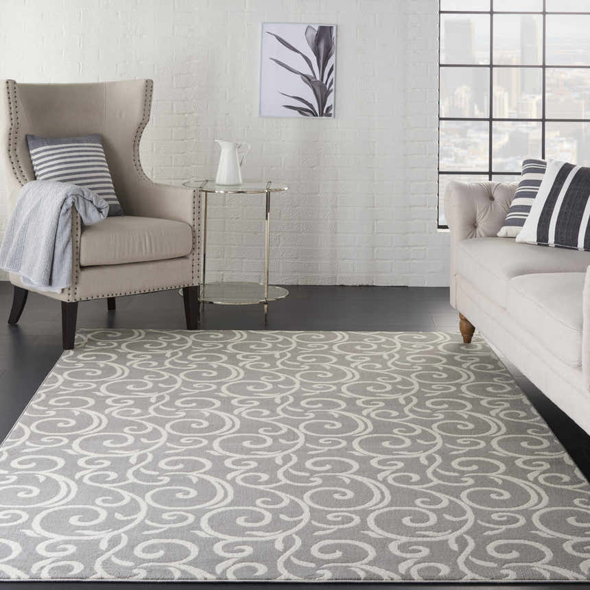 Living room scene with a Nourison Grafix Grey rug, beige sofa and chair, and white brick wall.