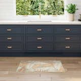 Kitchen scene with a Nourison Aloha Sage Rose rug, navy cabinets, and light wood floors.