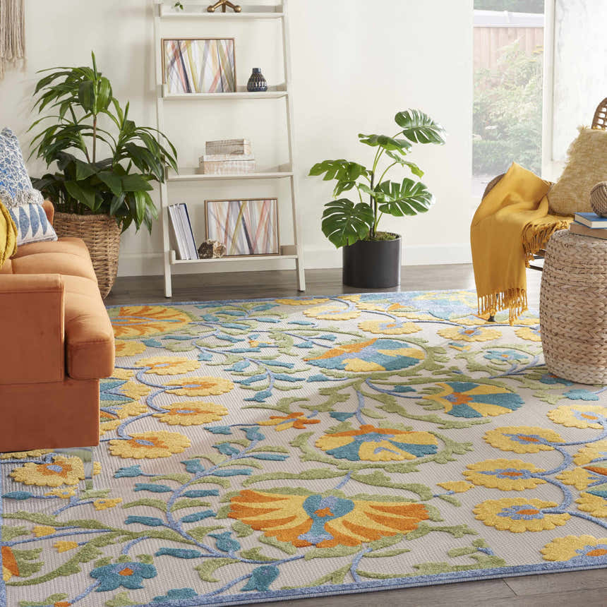 Living room scene with a Nourison Aloha Multicolor rug, orange sofa, and plants creating a bright, inviting space.