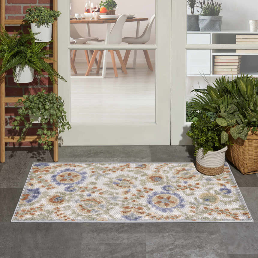Entryway scene with Nourison Aloha Ivory Blue Outdoor Area Rug, potted plants, and dining room view.