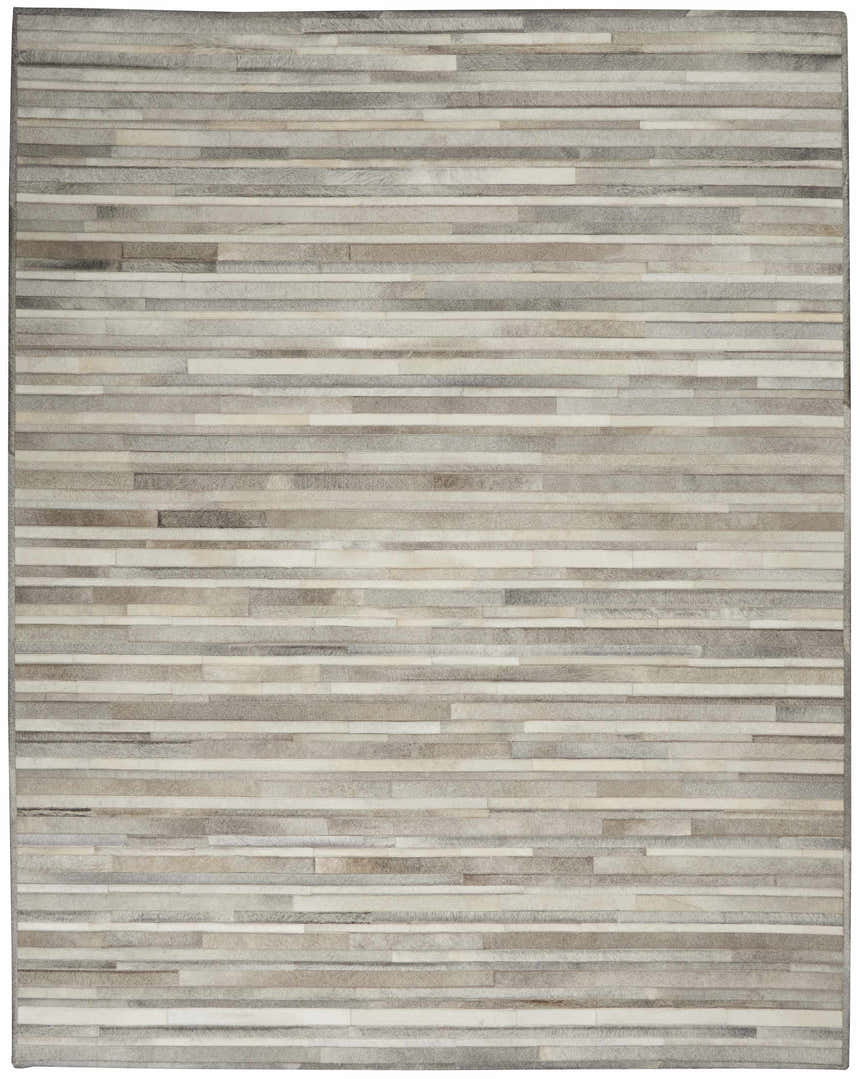 Close-up of the Calvin Klein Home Prairie Silver rug. Features a gray and silver striped pattern with a hair on hide texture.