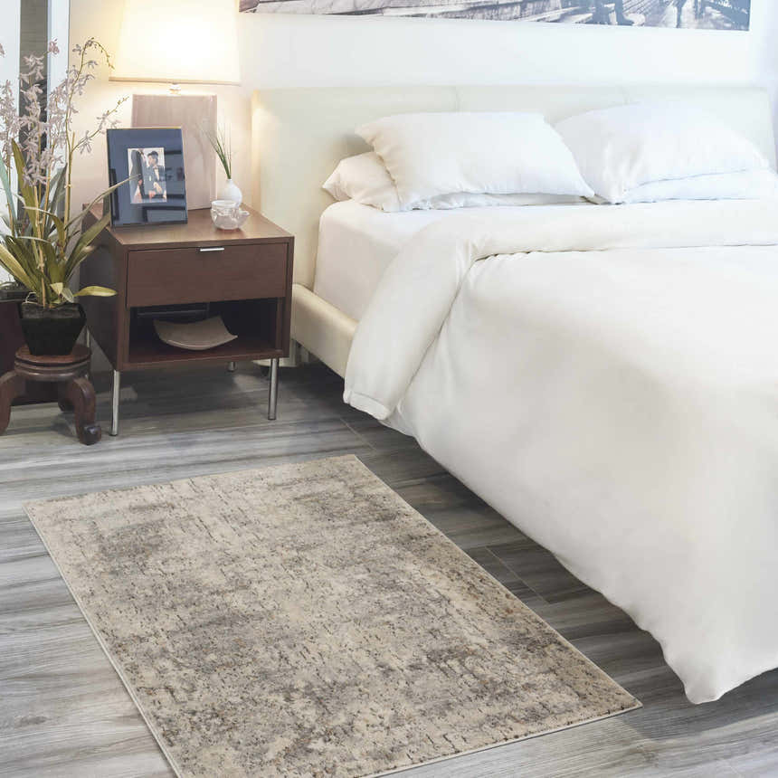 Bedroom scene with a Nourison Quarry Beige Gray rug, white bedding, and wood nightstand.