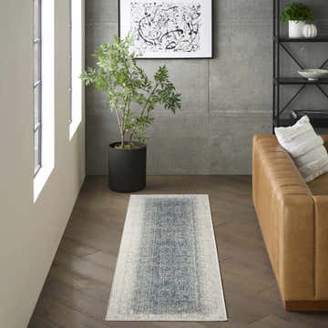 Modern living room with a chestnut leather sofa and DKNY Grand Street Ivory Blue Area Rug runner.