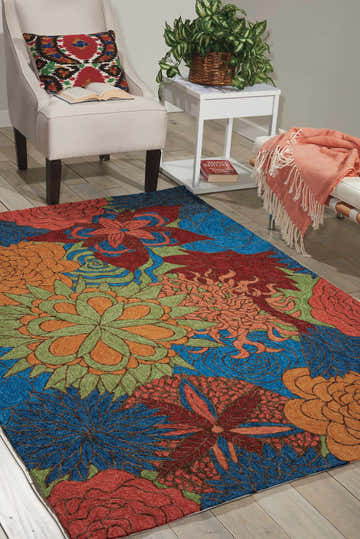 Living room scene with a blue Nourison South Beach area rug featuring a floral pattern, plus a chair, bench, and side table.