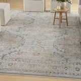 Living room scene with a light blue vintage Nourison Lynx area rug, white ottomans, and a small wood side table.