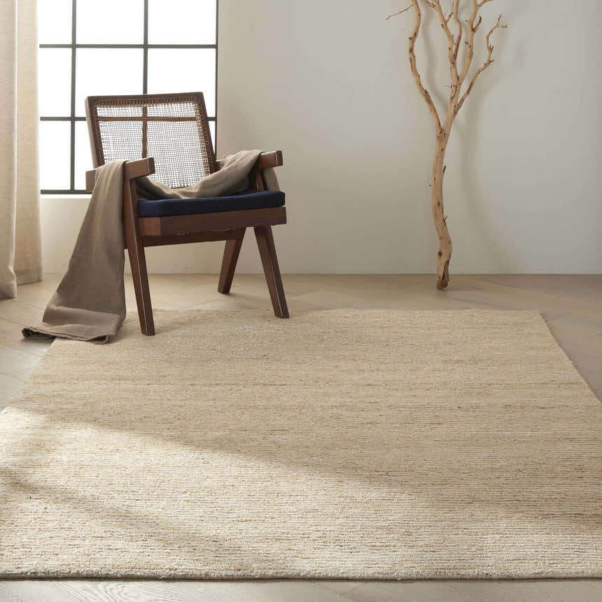 Minimalist room with Calvin Klein Mesa Gypsum rug, wood chair, and branch decor. Modern, neutral tones.