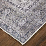 Close up of the Feizy Percy rug showing gray, ivory, and taupe medallion pattern and textured edge detail on wood floor. Corner