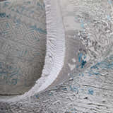 Close-up of the Feizy Cadiz rug showing its abstract blue, gray, and gold design and fringed edge. Fold