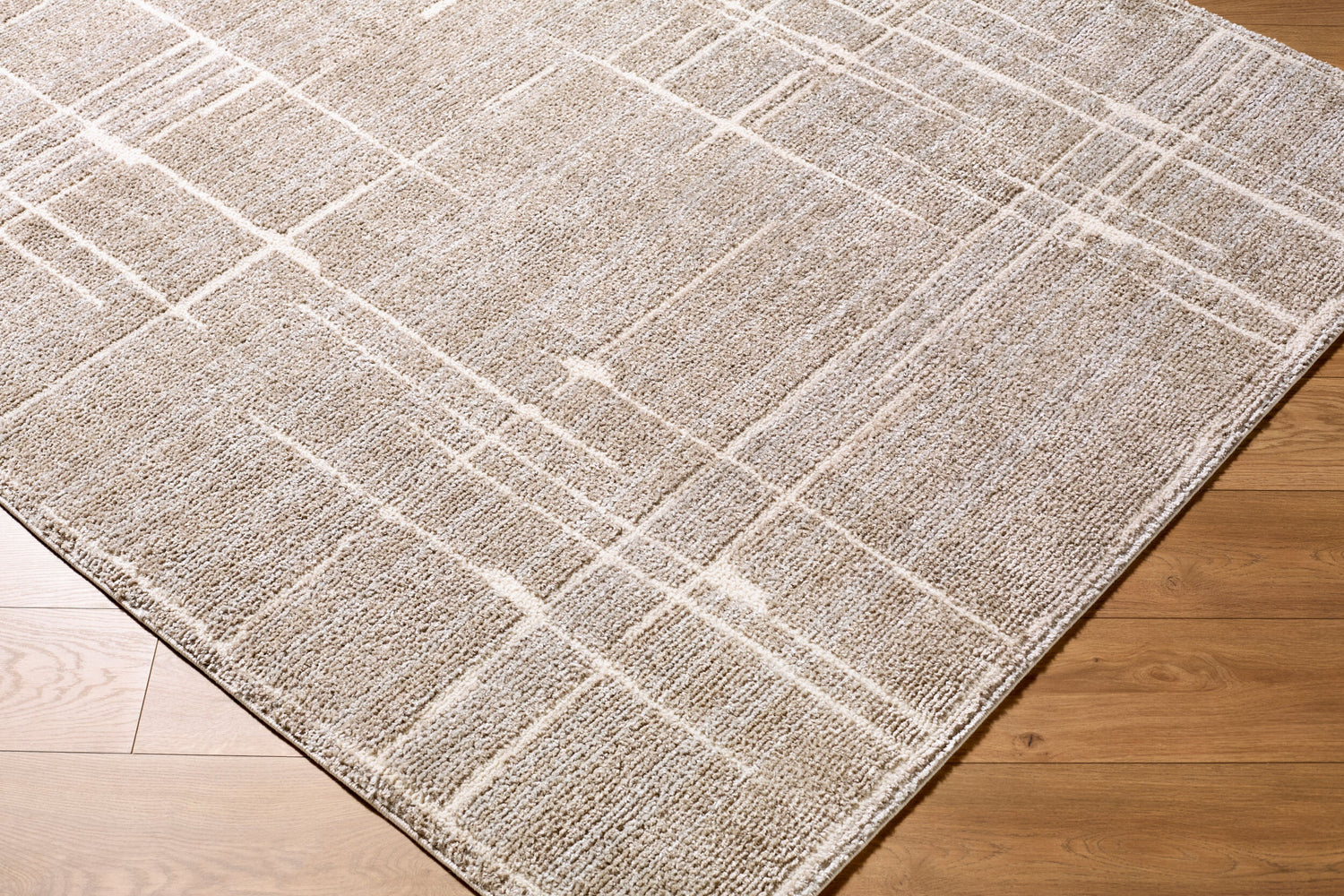 Close-up of Alma Machine Woven Elle Decor x LIVABLISS EDAL-2304 area rug with a geometric pattern in medium brown and taupe. Corner