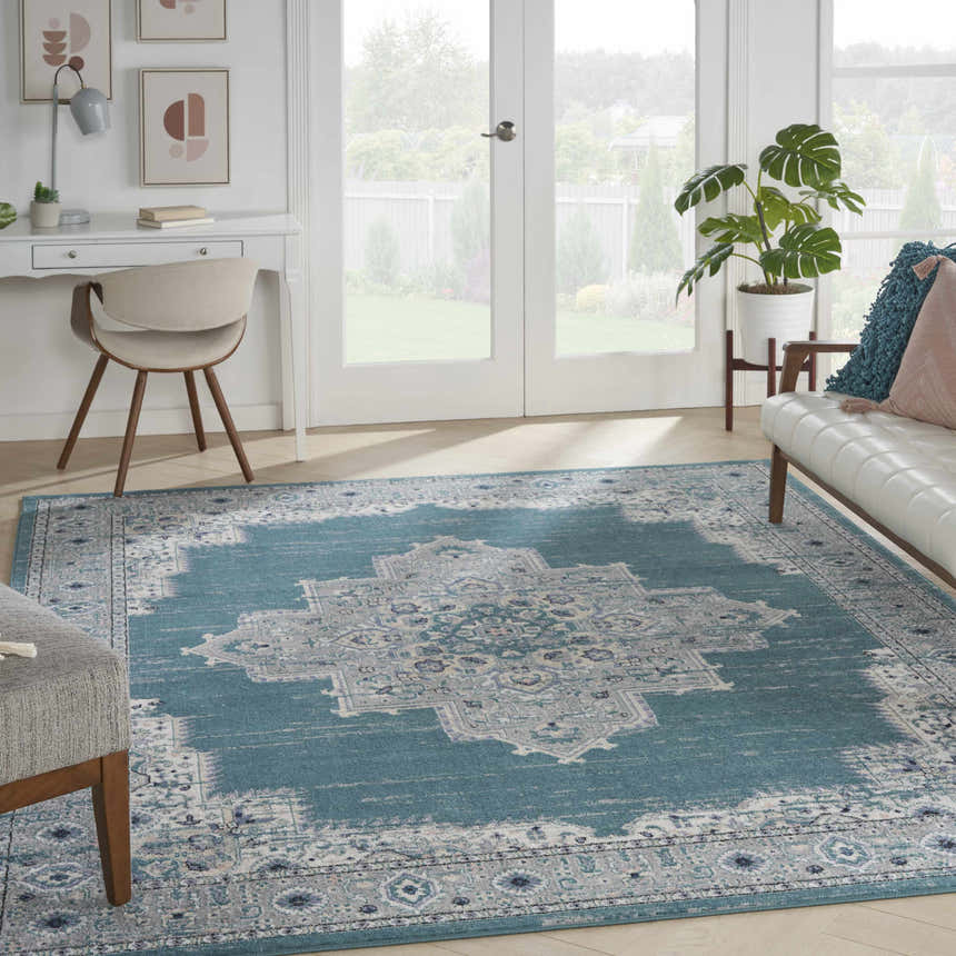 Bright sunroom with white desk, couch, and Nourison Passion Turquoise Grey Bohemian rug with a central medallion pattern.