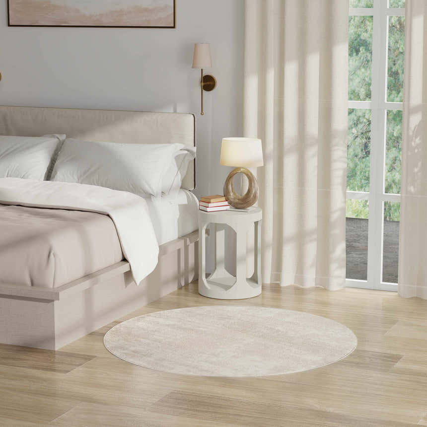 Serene bedroom with a round Nourison Serenity Home Ivory rug, bedside table, and neutral decor.