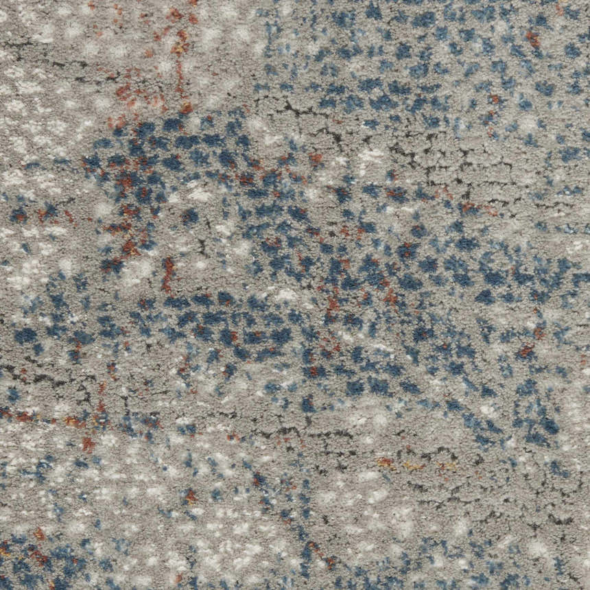 Close-up of the Nourison Rustic Textures Light Grey Blue rug. Features a textured, mottled pattern with blue, gray, and rust accents.