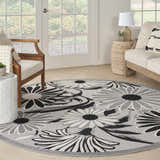Sunroom with a round Nourison Aloha Black White Outdoor Area Rug, sofa, and chair.