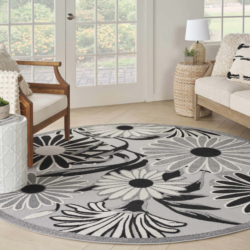 Sunroom with a round Nourison Aloha Black White Outdoor Area Rug, sofa, and chair.
