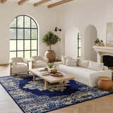 Living room scene with a Nourison Grafix Navy Blue Vintage rug, cream sofa and chairs, light wood floors, and arched windows.