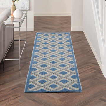 Hallway with a Nourison Aloha Blue Grey Modern Area Rug runner, wood floors, and a console table.