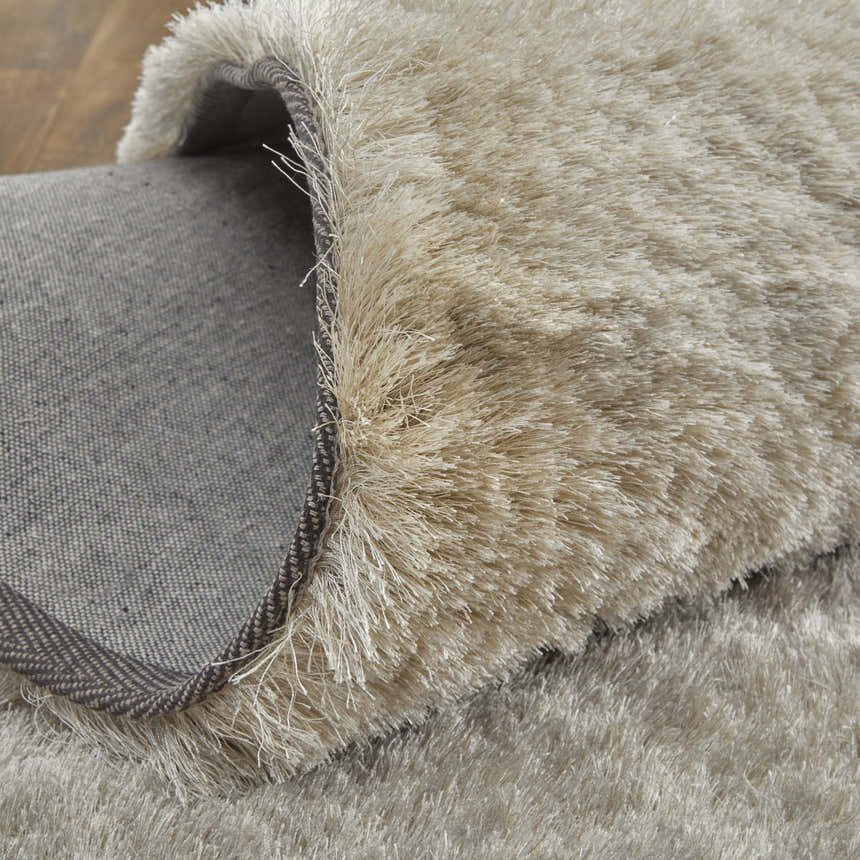 Close-up of the Feizy Indochine Modern Solid Tan/Taupe Area Rug showing the shag texture and backing. Fold