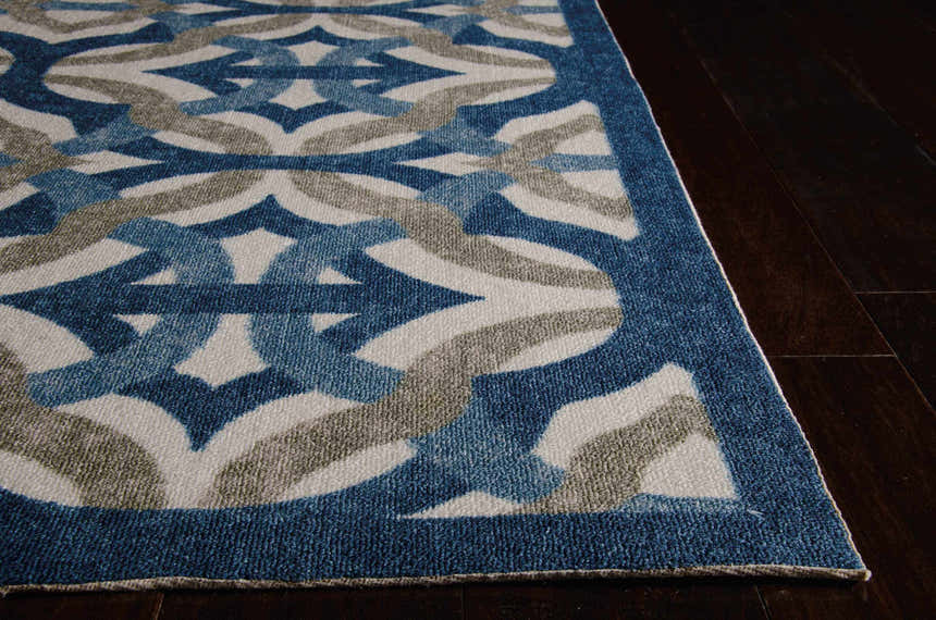 Close-up of the Celestial Waverly Sun N' Shade rug. Features a blue, gray, and white geometric pattern on dark wood floors.