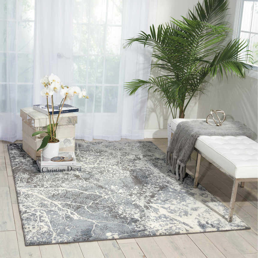 Bright living room with a Nourison Maxell Grey rug, white bench, and potted orchid. Modern, airy feel.