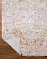 Close-up of the Rhody Luxe Rug, a traditional rug in light silver and sterling gray, on a wood floor. Fold