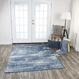Living room scene with Rizzy EN7262 area rug in blue and ivory, styled with a chair, stool, and throw blanket. Roomscene-Rectangle