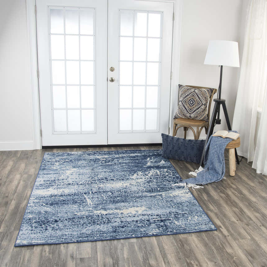 Living room scene with Rizzy EN7262 area rug in blue and ivory, styled with a chair, stool, and throw blanket. Roomscene-Rectangle