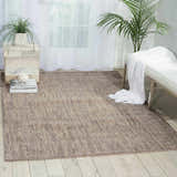 Light, airy room with Barclay Butera Intermix Smoke rug, white bench, and plants. Gray wool rug on wood floor.