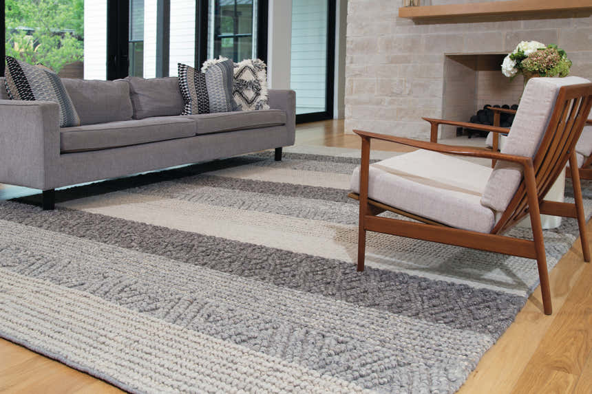 Living room scene with gray sofa and Feizy Berkeley Gray/Taupe/Tan rug under a wood chair, creating a modern, casual space. Roomscene-Rectangle