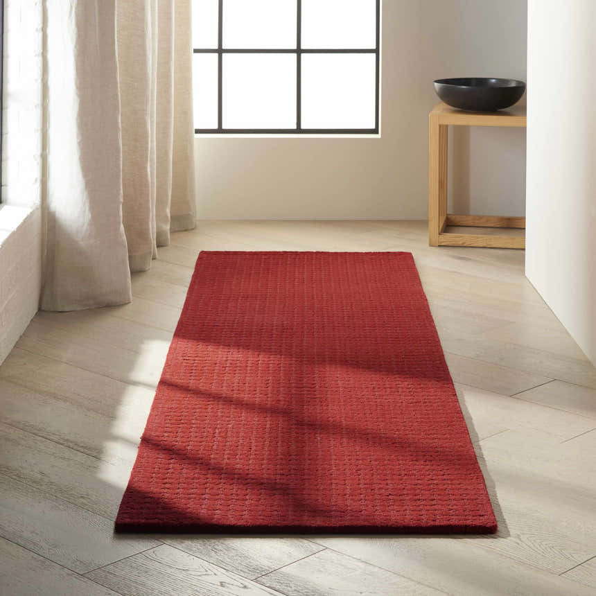 Minimalist room with a Calvin Klein Las Vegas Red Retro rug on light wood floors, near a window with linen curtains.