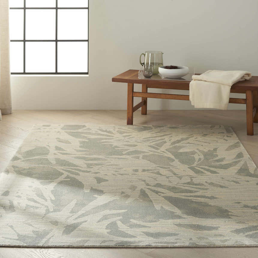 Minimalist room with Calvin Klein Home Maya Zinc/Paloma rug, wood bench, pitcher, and neutral decor.