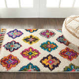 Entryway with Nourison Nomad Ivory Multicolor Floral Rug, white walls, dark wood floors, and a cream pouf.