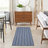 Modern dining room with a Nourison Twist Reversible Blue Area Rug, wood furniture, and white sofa.