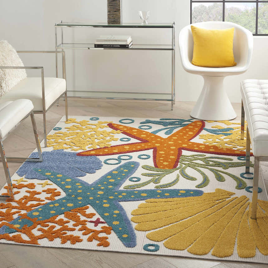 Coastal living room with white furniture and Nourison Aloha Multicolor area rug featuring starfish and seashell designs.
