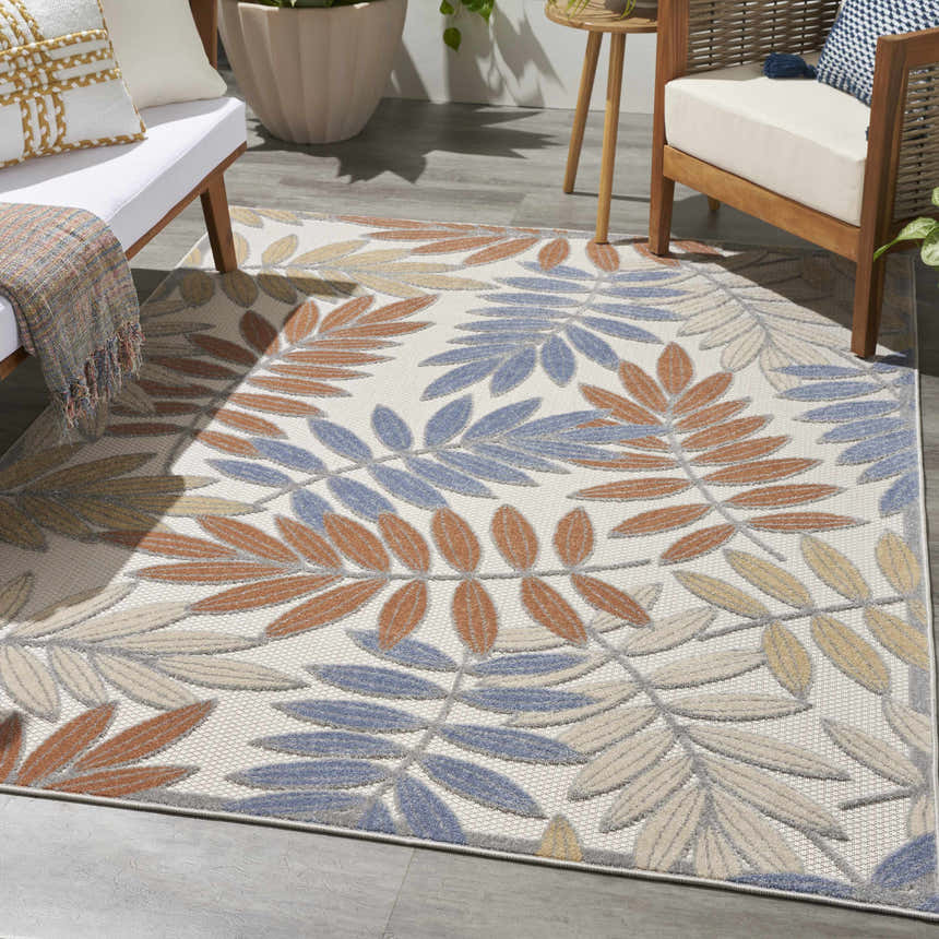 Outdoor patio scene with a Nourison Aloha Blue Mocha area rug featuring a leaf pattern.