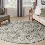 Living room with a round Nourison Oushak Home Charcoal rug, taupe sofa, and gray armchair. Vintage style.