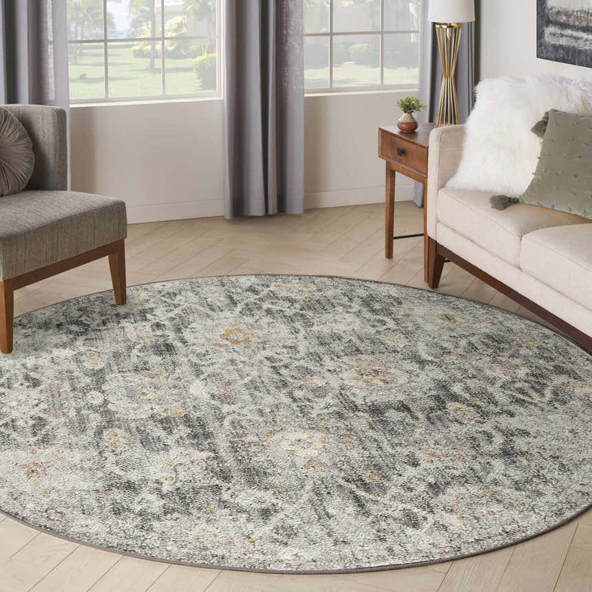 Living room with a round Nourison Oushak Home Charcoal rug, taupe sofa, and gray armchair. Vintage style.