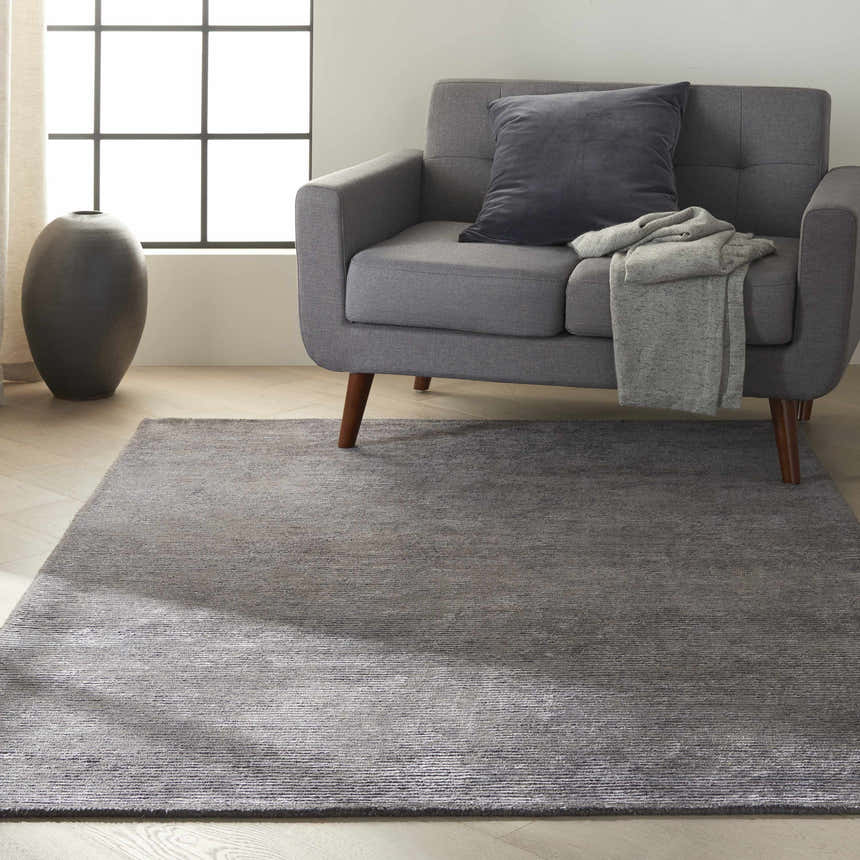 Living room scene with a gray sofa and the Calvin Klein Home Ravine Nightshade area rug.