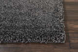 Close-up of the plush texture of the Nourison Malibu Shag Dark Grey rug on dark wood flooring.