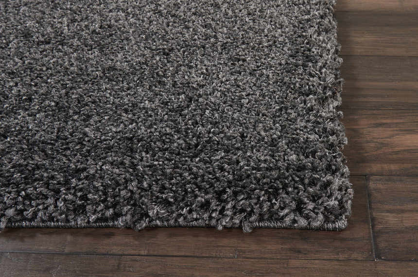 Close-up of the plush texture of the Nourison Malibu Shag Dark Grey rug on dark wood flooring.